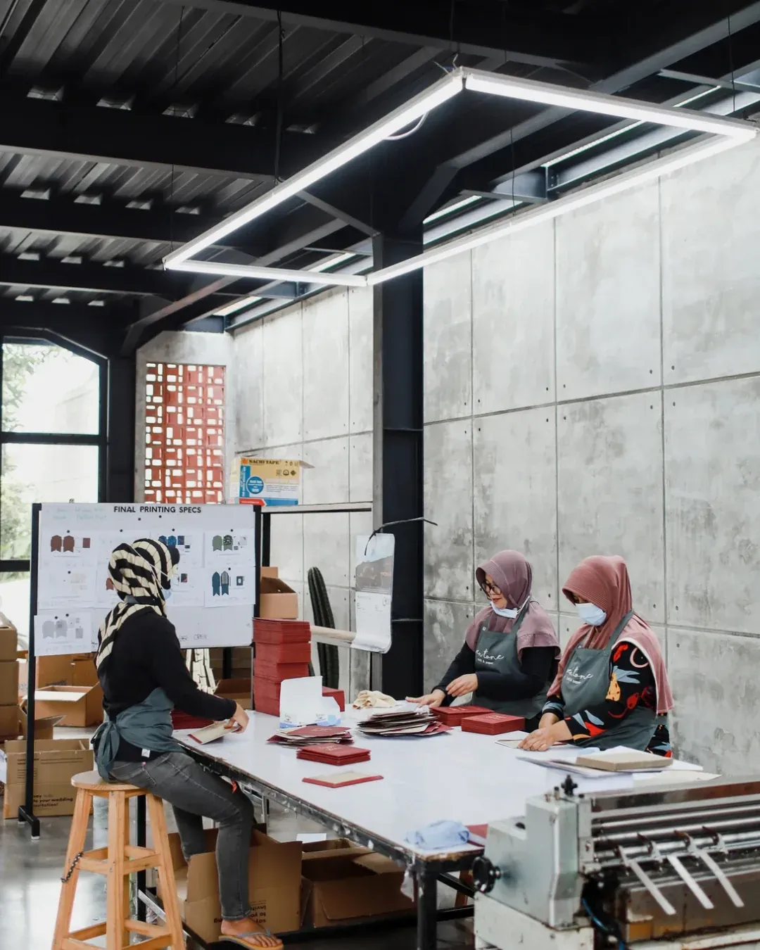 Tim workshop Pentone merapikan hasil cetak di meja produksi